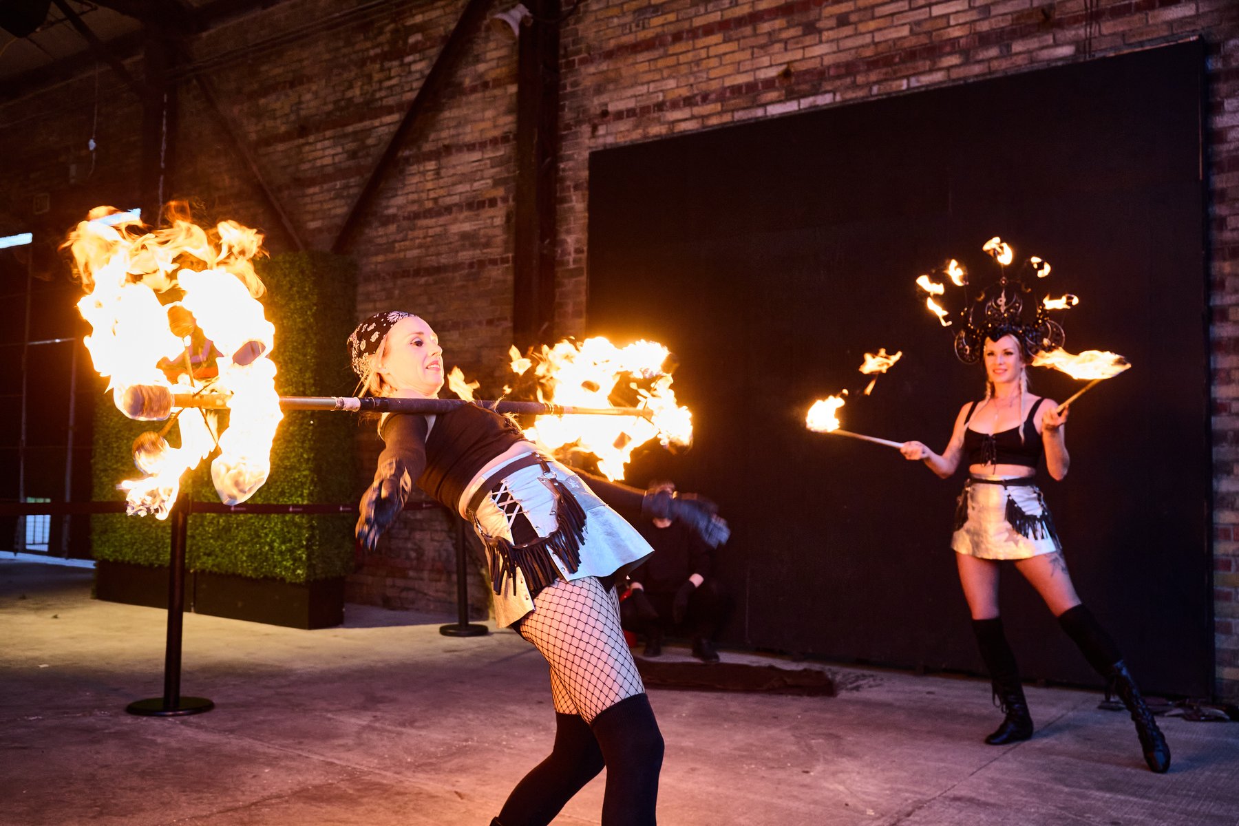 Two fire performers with flaming props against a graffiti wall