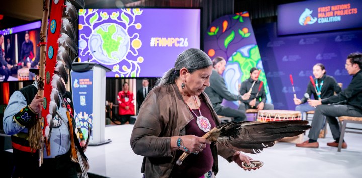 Elder holding an eagle feather fan on stage at the conference